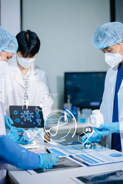 Medical team having a meeting with doctors in white lab coats and surgical scrubs seated at a table discussing a patients working online using computers