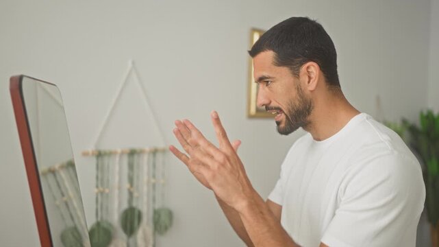 Man in white t shirt displays thumbs up and gesturing hands toward mirror in studio, alternating clapping and pointing in a short sequence; encouragement self reflection progress.