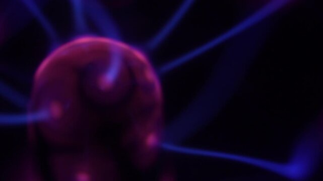 A close-up of a plasma ball coil that creates energy beams in shades of purple.