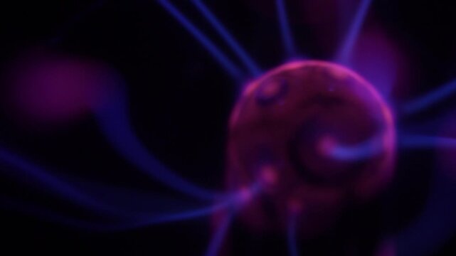 A close-up of a plasma ball coil that creates energy beams in shades of purple.