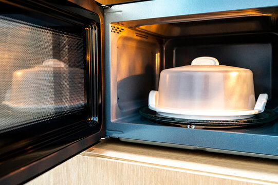 Open door microwave oven with plastic plate cover inside. Home appliance in the kitchen