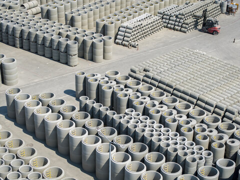 Aerial view of rows of concrete precast pipe sections stored in a yard with a forklift operating nearby in Krakow, Lesser Poland Voivode, Poland.