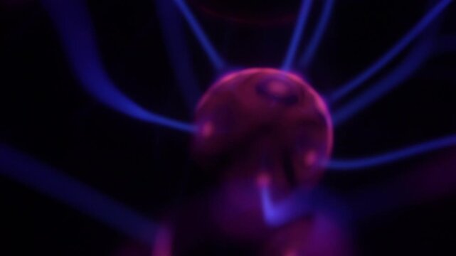 A close-up of a plasma ball coil that creates energy beams in shades of purple.