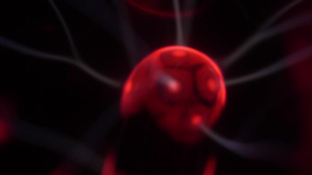Close-up of a plasma ball coil that creates red and white energy beams.
