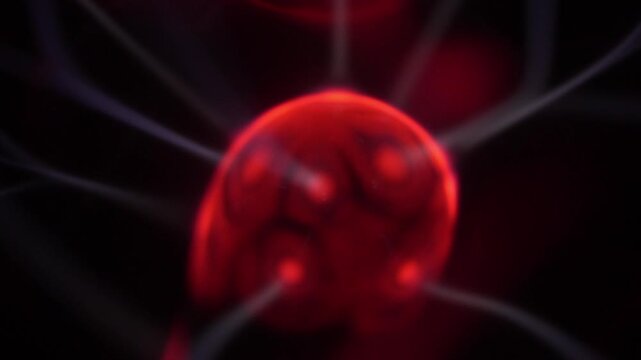 Close-up of a plasma ball coil that creates red and white energy beams.