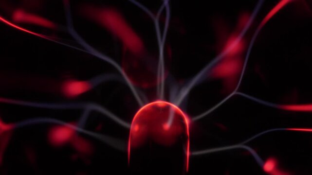 Close-up of a plasma ball coil. The plasma ball creates beams of energy in red and white.