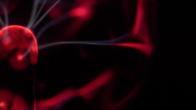 Close-up of the discharge rays of a plasma ball in shades of red and white.