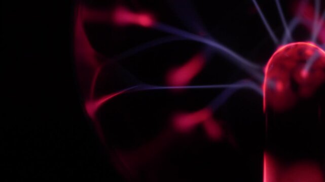 Close-up of the discharge rays of a plasma ball in shades of red and white.