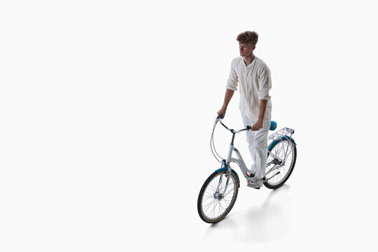 Young man cycles toward camera on city bicycle isolated on white. Concept of active daily commuting, cardiovascular fitness routine, accessible urban transportation.
