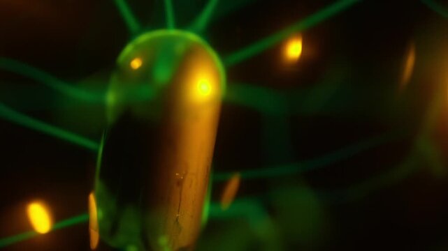 A close-up of the working coil of a plasma ball, which creates green electrical discharges. A warm beam of light illuminates the interior of the plasma ball in the beam.
