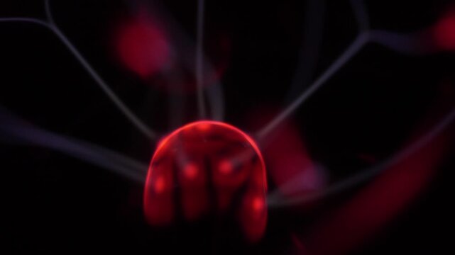 Close-up of the plasma ball coil during operation. The plasma ball generates red and white rays.