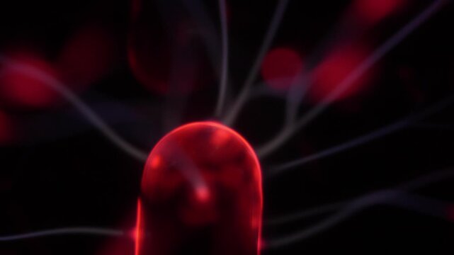 Close-up of the plasma ball coil during operation. The plasma ball generates red and white rays.