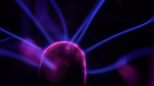 Close-up of the plasma ball coil during operation. The plasma ball generates purple-hued rays.