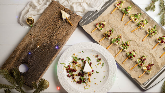 Tree shaped brie cheese appetizers with pomegranate, walnuts, cilantro and a pretzel stick
