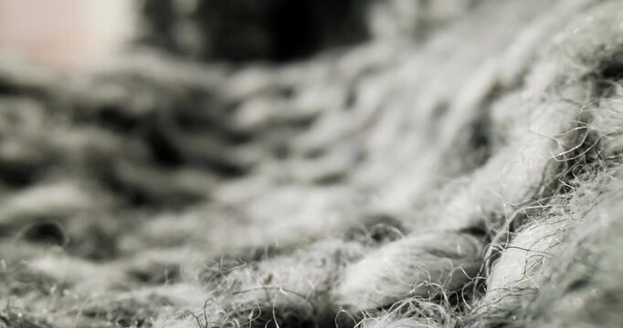 Slow motion macro tracking over gray wool yarn fibers on knit fabric in studio indoor close up tracking forward, macro probe lens.