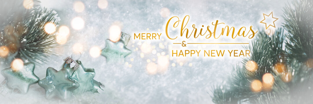 Wonderful winter background image with frosted pine branches. Poinsettias with festive golden bokeh lights in snow. Perfect for a english christmas greeting card.