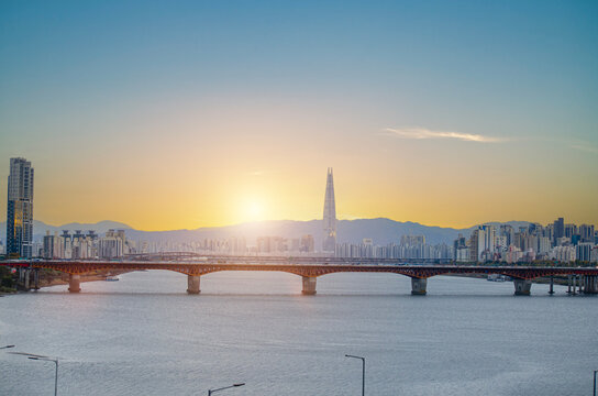 SEOUL, SOUTH KOREA - December 22, 2025: Scenery of Lotte Tower with bridge railway transport over the han river and city town landscape on golden sky cuold clear before sunset