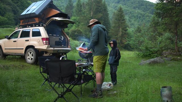 Father and son cooking barbecue while overlanding