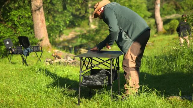 Adventurer assembling a camping table in the forest