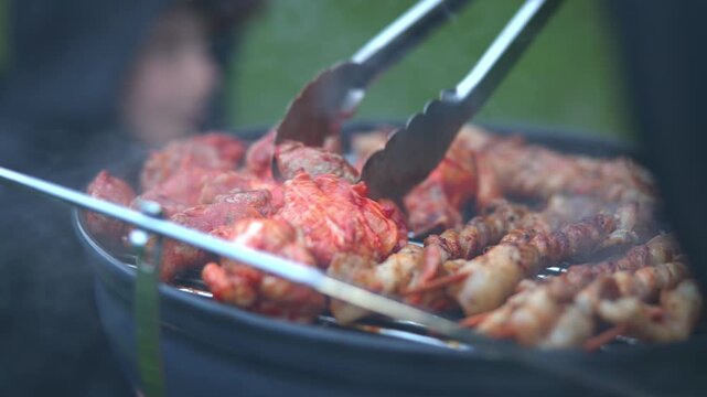 Person cooking lobster tails and prawns on barbecue grill
