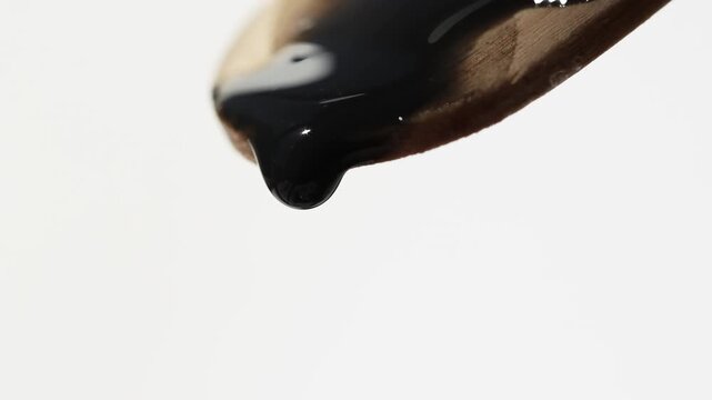 Black cosmetic texture slowly dripping, front macro view.