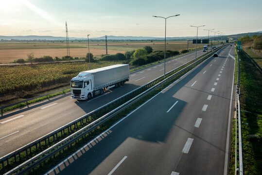 Transportation truck with semi-trailer driving along highway on the sunset background. Services and Transport logistics. Modern Lorry Transport concept. Long Self-driving lorries