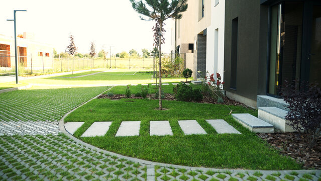 Modern house creating a green garden with stepping stones leading to the entrance and eco-friendly permeable paving