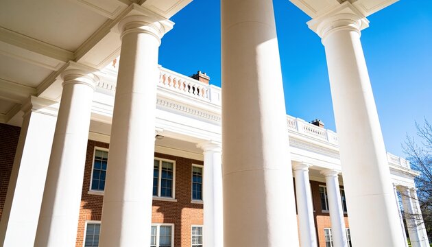 Framing tall white classical columns drawing eye upward at college portico, red brick facade rising