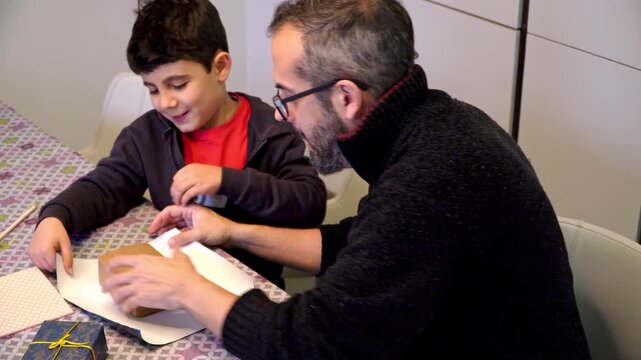 Father and son decorating Christmas gift boxes at home