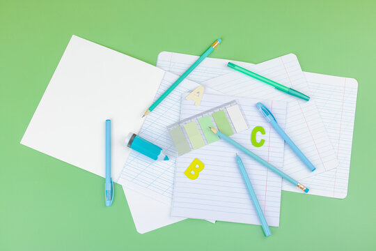 Back-to-school concept, flat lay composition of school supplies on a green background