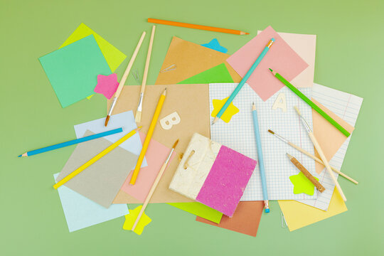 Eco-friendly school supplies on green background. Paper, wooden pencils, brushes, notebooks
