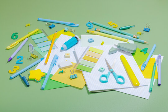 Back-to-school concept, flat lay composition of school supplies on a green background