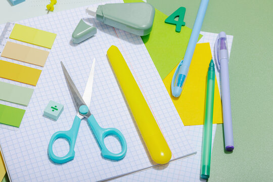 Back-to-school concept, flat lay composition of school supplies on a green background
