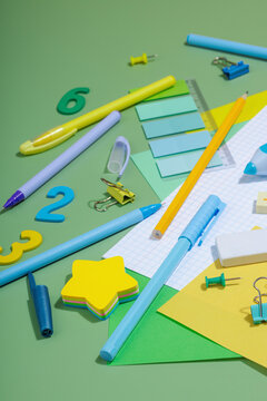 Back-to-school concept, flat lay composition of school supplies on a green background