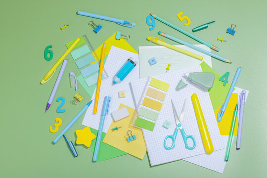 Back-to-school concept, flat lay composition of school supplies on a green background