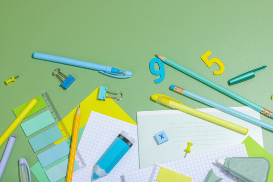 Back-to-school concept, flat lay composition of school supplies on a green background
