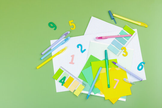 Back-to-school concept, flat lay composition of school supplies on a green background