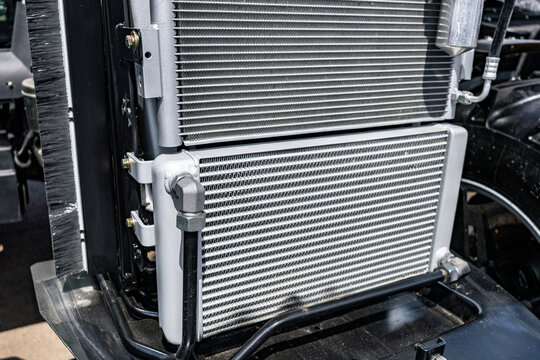 Agricultural tractor engine cooling radiators package. Modern farm machinery cooling system section with a c condenser, oil intercooler, receiver drier and industrial transport vehicle details.