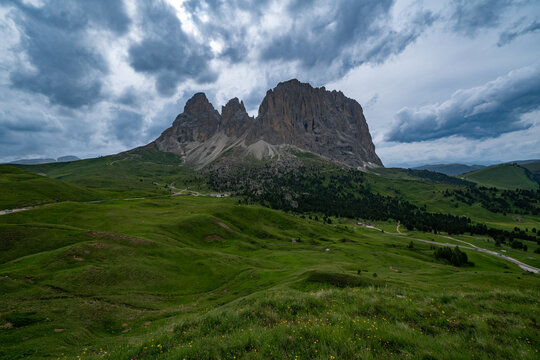 Alpine landscape with rugged dolomite peaks under a bright blue sky and fluffy white clouds, mountains