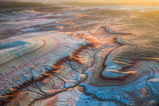 Aerial view of the colorful striped rock formations of Kyzyl Kup, known as Tiramisu, with intricate erosion patterns and golden hour light in Karakiya District, Mangystau Region, Kazakhstan.