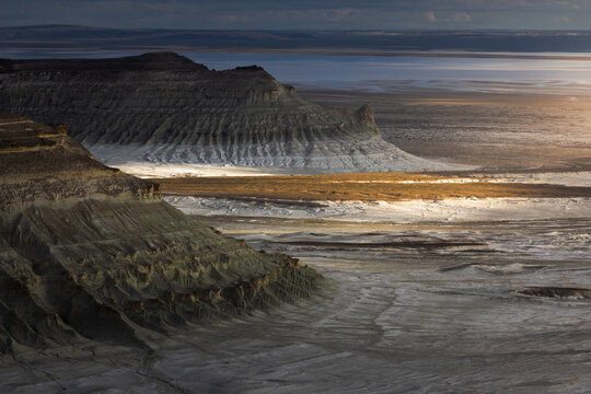 Aerial view of the dramatic limestone formations and desert landscape of the Bozjyra canyon, with rugged cliffs and salt flats in Aktau, Mangystau Region, Kazakhstan.