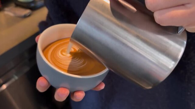 Barista pouring milk for intricate winged heart rosette latte art