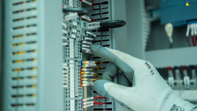 Close up hand engineer checking electrical control panel at factory electrical city. Technician working repair system control electronics PLC. Maintenance manufacturing industry. 