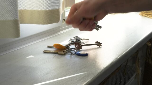  A man&rsquo;s hands pick up the door keys lying on the table. Pick up the bunch of keys for the door lock.