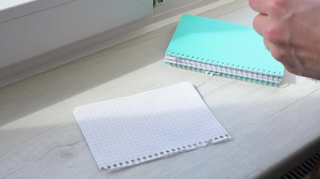 Stack the blank white sheets of paper torn from a notepad on the table. Stack the white sheets in a grid pattern on the table.