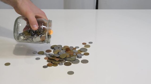 Pour the coins out of the jar onto the table. The concept of a home money box, saving money and keeping it safe in a money box.