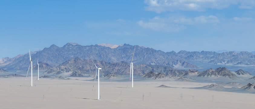 Wind Turbines In Arid Gobi Desert Landscape With Rugged Mountains Background
