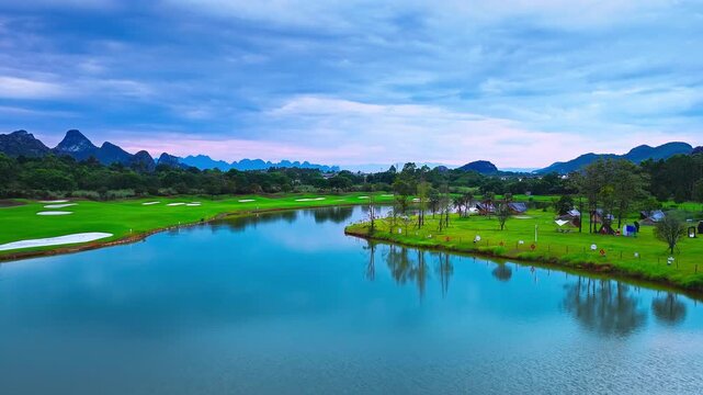 Guangxi, China features a lakeside golf course, manicured fairways, and karst peaks beneath a blue cloudy sky, ideal for travel and tourism.