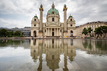 Naklejka premium Karlskirchen Baroque church reflecting on still water pool in Vienna Austria on overcast day