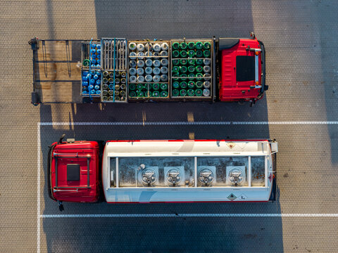 Aerial view of two red trucks parked in a paved lot at the GP Groot collection and recycling facility in Alkmaar, Noord-Holland, Netherlands.